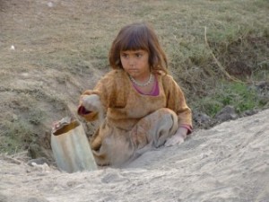 Young Afghan refugee girl playing in the dirt