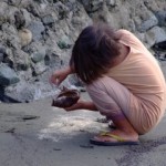 Girl playing with coconut and sand on the beach