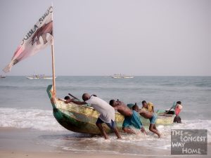 Ghanaians heaving a fishing boat onto a beach