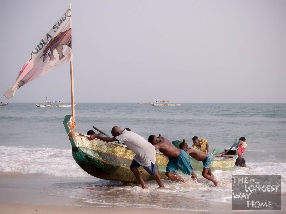 Ghanaians heaving a fishing boat onto a beach