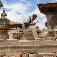 Stone mason working on restoring the Vatsala Durga temple in Bhaktapur Nepal