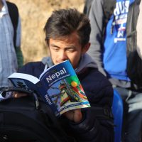 Boy reading from a Nepal guidebook